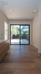 Obraz premium A modern bathroom under construction with large floor-to-ceiling windows, light wood finishes, and an open layout offering views of a backyard patio.