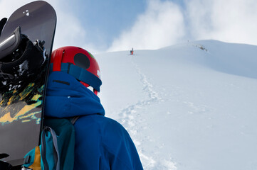Cheerful and happy man in warm blue jacket, ski mask and helmet looking away, spending extreme...
