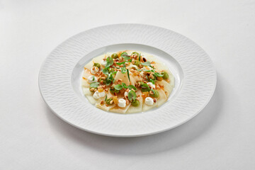 A fresh and healthy seafood dish featuring a delicate piece of white fish carpaccio, surrounded by...