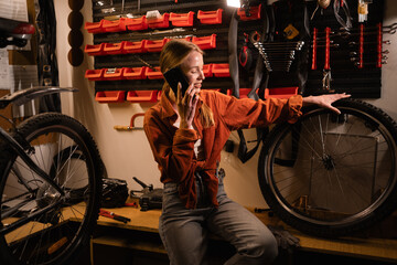 Repair Bicycle in garage. woman small business owner or mechanic using cellphone in workshop....