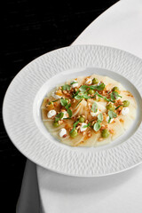 A fresh and healthy seafood dish featuring a delicate piece of white fish carpaccio, surrounded by a colorful array of fresh vegetables