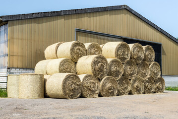Stacked hay bales in the front of barn on a farm
