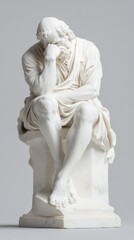 A marble statue of a seated philosopher, deeply in thought. The statue is isolated against a plain background, highlighting its detailed craftsmanship.