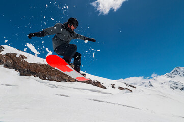 Flying snowboarder in the mountains, extreme sport. Wide angle on the flight in the jump of the snowboarder
