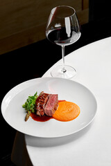 A gourmet dish featuring a perfectly cooked steak, served with a side of creamy mashed potatoes and a vibrant green vegetable.