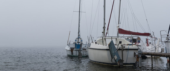 LANDSCAPE BY THE LAKE - A sailboats at the pier on a foggy day

