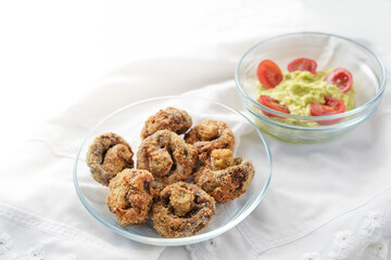 Breaded mushrooms baked in a hot air fryer and avocado guacamole dip in glass bowls on a white napkin, copy space