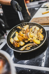 A skillet with sautéed potatoes and mushrooms is placed on a stove. Steam rises, hinting at the delicious cooking process. The scene captures the essence of vibrant kitchen activity.