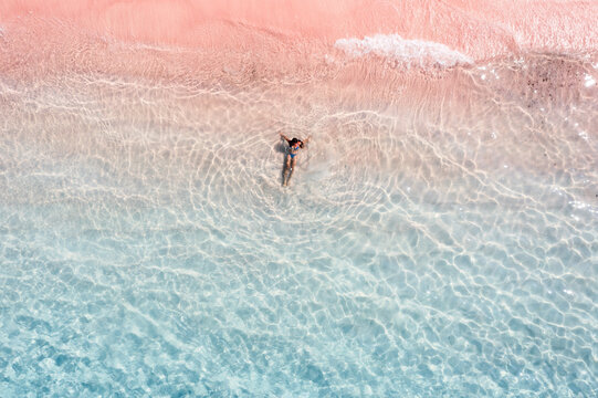 Aerial view of woman lying down at pink sand beach, Indonesia