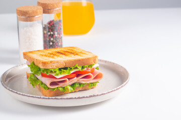 Close-up of two sandwiches with bacon, salami, prosciutto and fresh vegetables on rustic wooden cutting board. Club sandwich concept