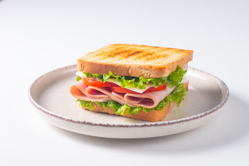 Close-up of two sandwiches with bacon, salami, prosciutto and fresh vegetables on rustic wooden cutting board. Club sandwich concept