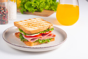 Close-up of two sandwiches with bacon, salami, prosciutto and fresh vegetables on rustic wooden cutting board. Club sandwich concept
