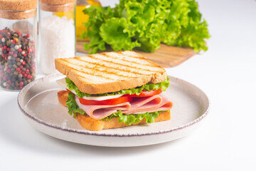 Close-up of two sandwiches with bacon, salami, prosciutto and fresh vegetables on rustic wooden cutting board. Club sandwich concept