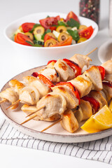 Delicious grilled chicken skewers with capsicum, lemon, salad and ketchup on a plate over the table. Chicken kebab. Healthy food concept.