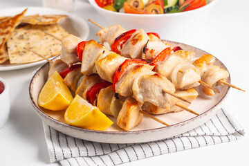 Delicious grilled chicken skewers with capsicum, lemon, salad and ketchup on a plate over the table. Chicken kebab. Healthy food concept.