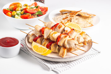Delicious grilled chicken skewers with capsicum, lemon, salad and ketchup on a plate over the table. Chicken kebab. Healthy food concept.