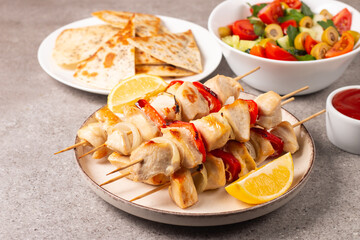Delicious grilled chicken skewers with capsicum, lemon, salad and ketchup on a plate over the table. Chicken kebab. Healthy food concept.