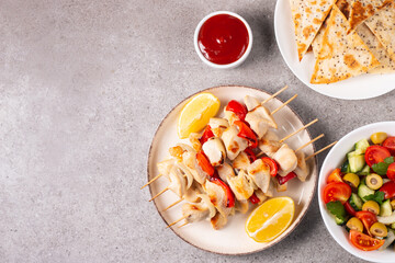 Delicious grilled chicken skewers with capsicum, lemon, salad and ketchup on a plate over the table. Chicken kebab. Healthy food concept.