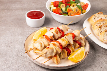 Delicious grilled chicken skewers with capsicum, lemon, salad and ketchup on a plate over the table. Chicken kebab. Healthy food concept.