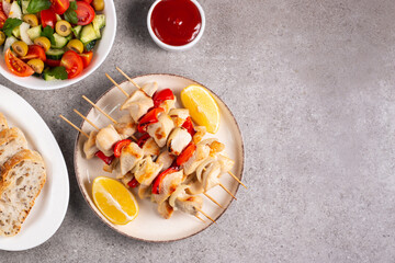 Delicious grilled chicken skewers with capsicum, lemon, salad and ketchup on a plate over the table. Chicken kebab. Healthy food concept.