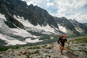 Fototapeta premium a tourist girl with a backpack walks through the Altai mountains in summer