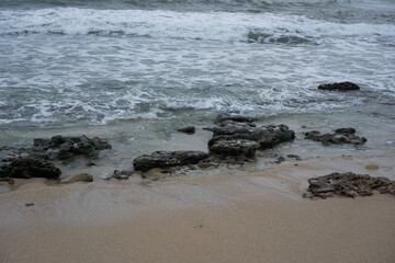 Tidal Waves Washing Rocks on a Sandy Beach at Dusk