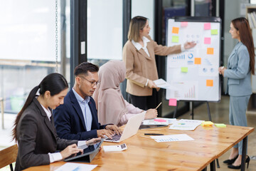 Group of asian professionals collaborating and working together in a  office. They are discussing project solutions and working on paperwork. The team looks happy, successful.

