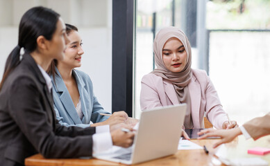 Group of asian professionals collaborating and working together in a  office. They are discussing project solutions and working on paperwork. The team looks happy, successful.
