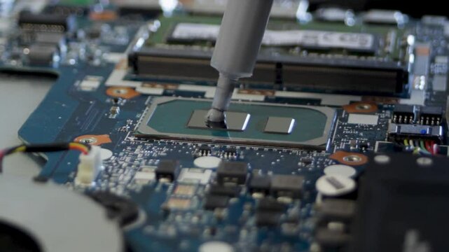 Applying thermal paste to the silicon crystal of the processor. A syringe squeezes thermal paste onto the processor.