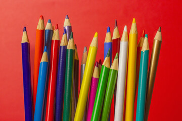 Vibrant Array of Colored Pencils Against a Bold Red Background.