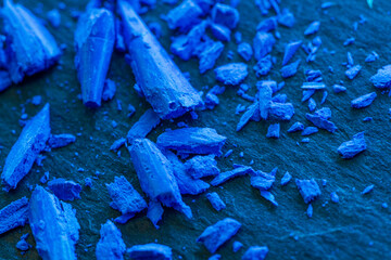 Vibrant Blue Chalk Fragments on Slate Surface.