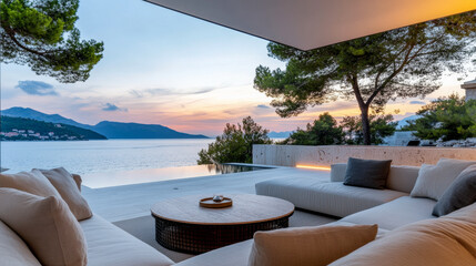 Fototapeta premium Elegant outdoor lounge area overlooking tranquil water and mountains during sunset