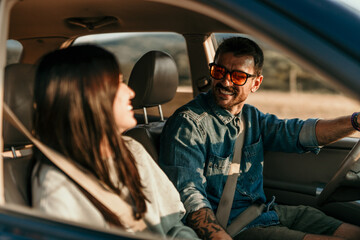 Carefree couple enjoying a golden hour road trip in their car