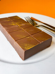 on a plate lies a bar of Dubai chocolate, next to a fork and knife
