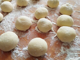 Preparation of traditional Ukrainian pampukh for Christmas holidays. Festive homemade Ukrainian food. Raw pampukh prepared on a wooden surface.