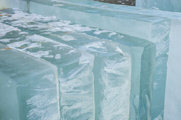 Transparent blocks of ice arranged in a natural setting during daylight reveal intricate textures...