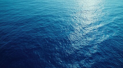 Aerial shot of tranquil blue ocean surface with reflective sunlight ideal for blank space and text overlay applications