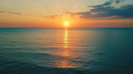 Obraz premium Aerial view of serene turquoise ocean waves reflecting golden sunset light on calm waters during a picturesque evening sky