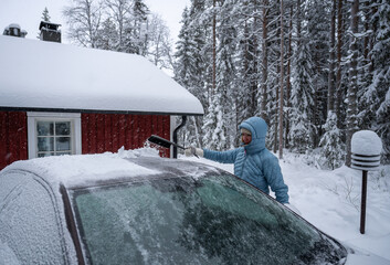 Woman remove her car from snow with brush. Car wash concept.