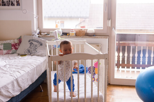 baby in a white baby cot standing