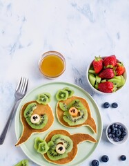 Funny fish shaped pancakes decorated with kiwi and banana for kids breakfast