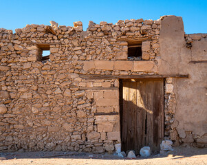A crumbling wall and wood doorway of an abandoned derelict building at Khraibeh Beach, a coastal village on the Red Sea shoreline of Neom in Tabuk Province, Saudi Arabia.