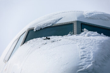 Snow covered cockpit of passenger airplane before de-icing process. Winter day at airport..