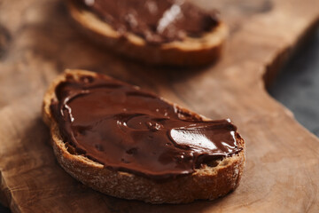 Ciabatta slices with chocolate spread on olive wood board