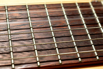 Guitar with wooden brown neck and strings. Close-up.
