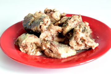 Pieces of canned mackerel fish lie on a plate, ready to eat.