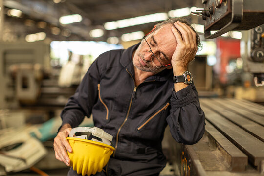 Senior engineer worker tired exhausted sleep nap at work in heavy industry factory.
