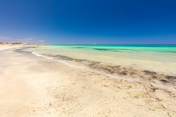 Krajobraz morski, piaszczysta plaża i wybrzeże, żółty piasek, widok na lazurowe morze, niebieski kolor nieba, wyspa Djerba, Tunezja. Tapeta, egzotyczne tło © anettastar