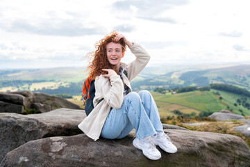 Young woman enjoying a beautiful landscape while sitting on a rock in the countryside