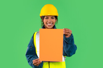 Construction worker smiling and holding an orange sheet against a green background